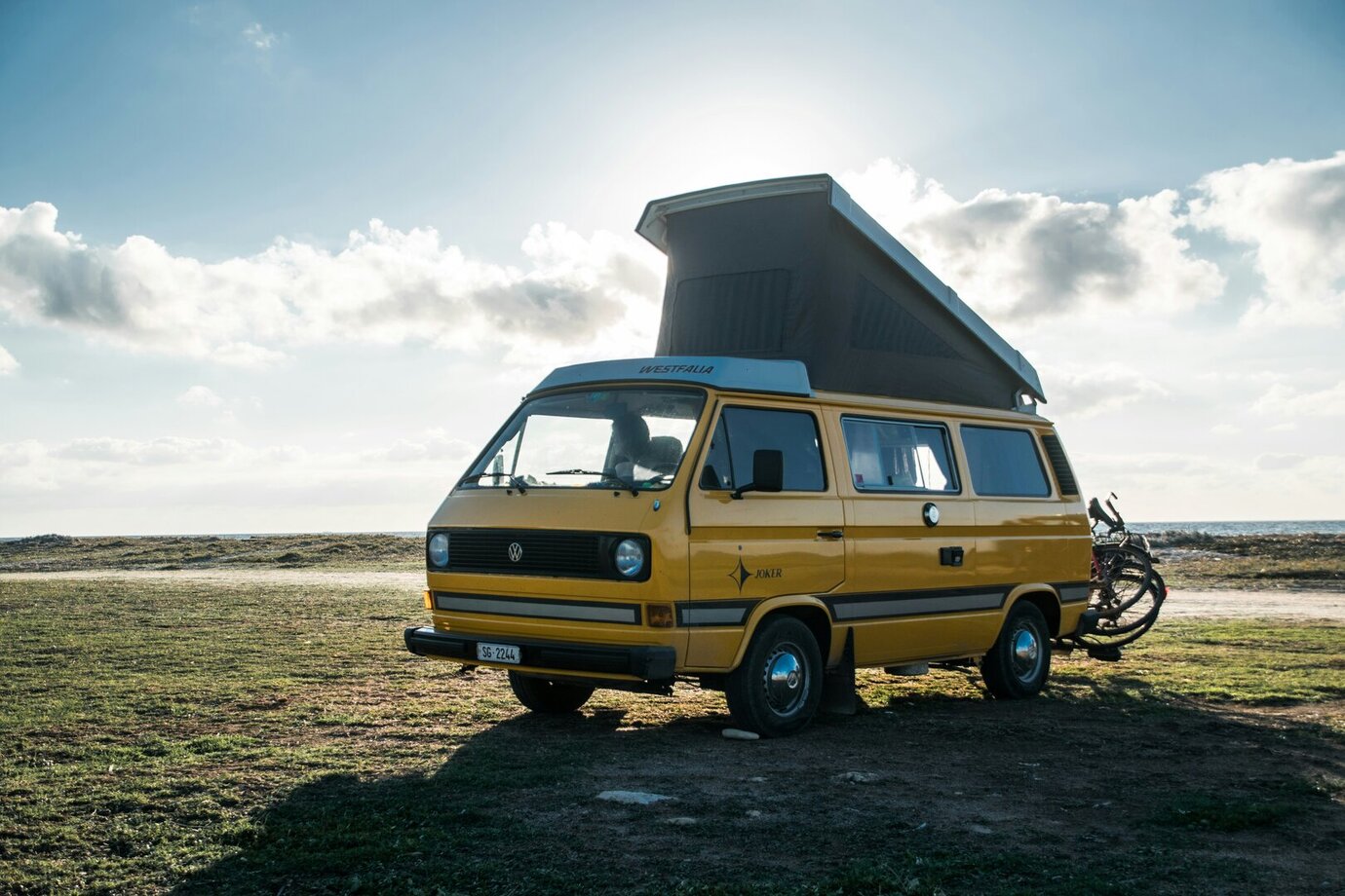 Gelbes VW-Bus-Wohnmobil mit Hochdach und zwei an der Heckklappe montierten E-Bikes.